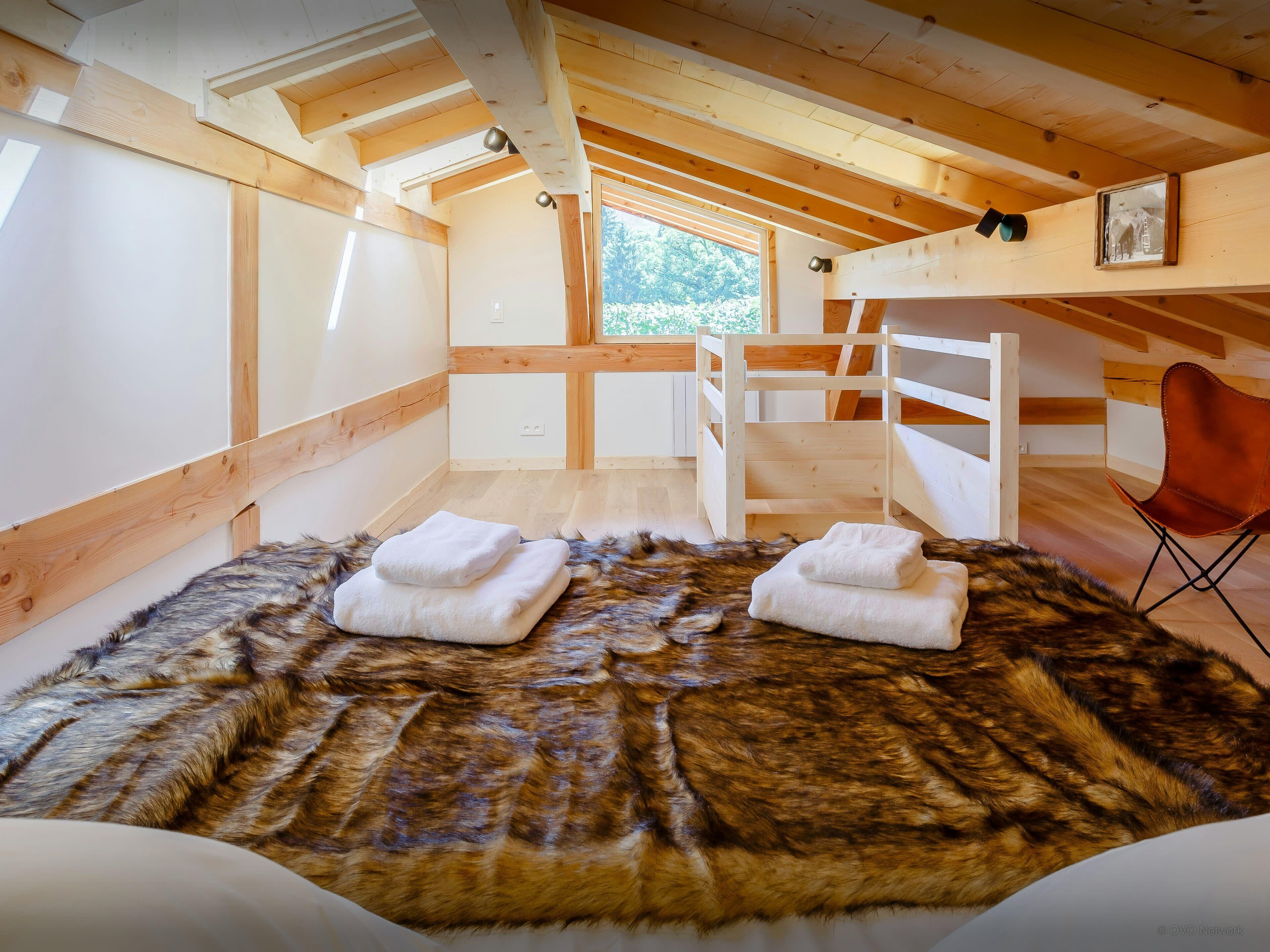 A cozy room with a wooden ceiling, a fur rug, and a chair.