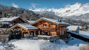 Un chalet en bois doté d’un balcon, entouré de montagnes enneigées.