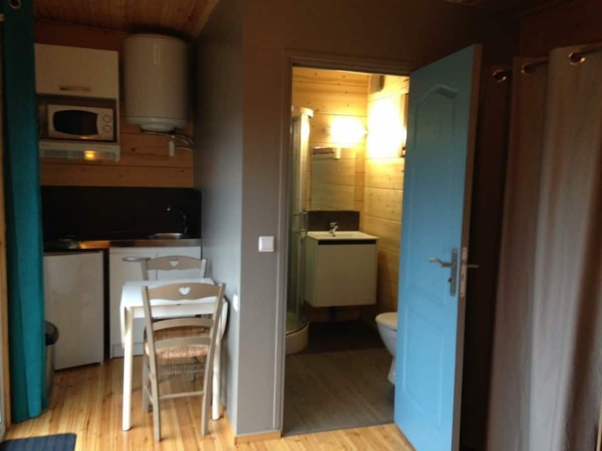 A compact kitchen with a microwave, a small refrigerator, and a dining table with chairs.