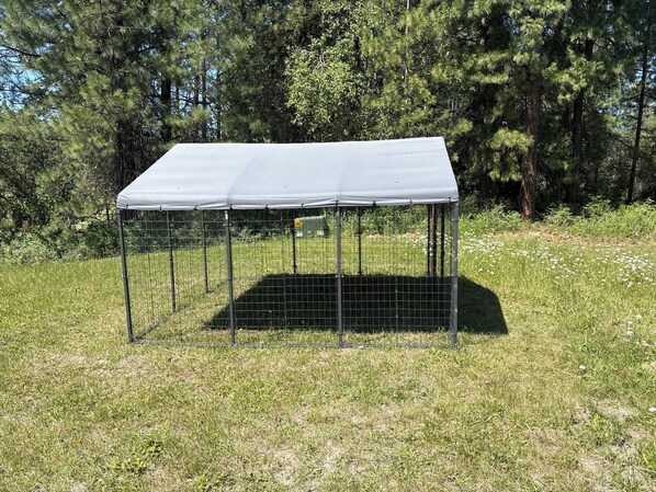 Un área exterior cercada con una estructura de techo metálico.