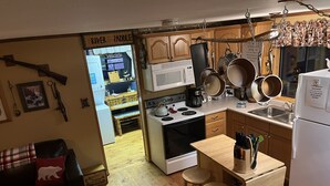 A compact kitchen with a stove, microwave, and wooden stools. A sign reads "Welcome to the River Paddle."
