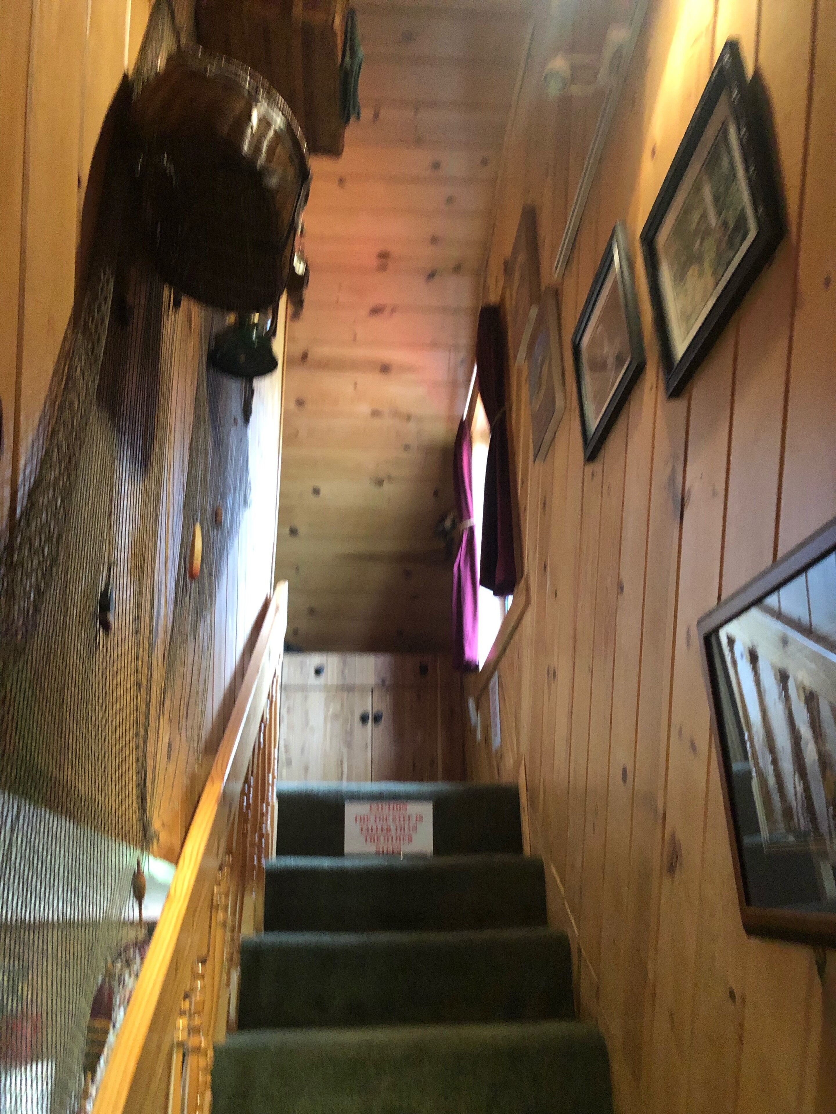 Una escala de fusta amb barana, que condueix a una habitació amb sostre i parets de fusta.