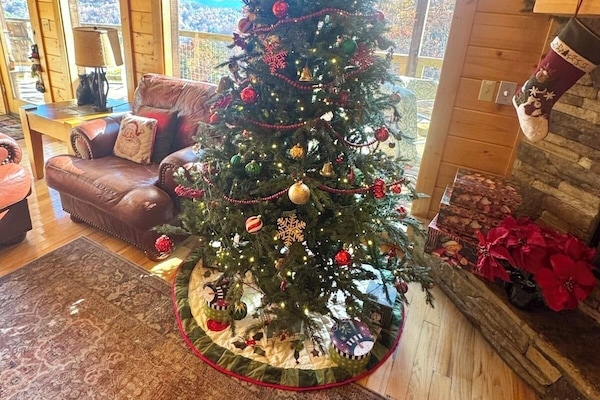 Cozy up by the crackling fireplace beside a beautifully decorated Christmas tree, where twinkling lights and stockings bring the cabin’s holiday spirit to life.