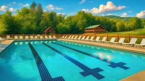 Une piscine avec des chaises longues et un chalet en bois situé dans une zone boisée.