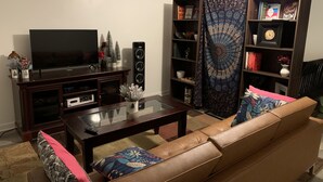 Ein Wohnzimmer mit Fernseher, Bücherregal und einer Couch.
