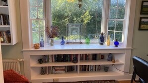 A bay window with bookshelves, decorative items, and a view of greenery outside.
