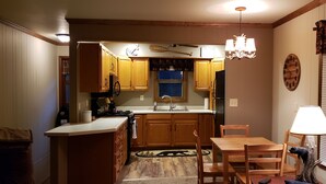 Una cocina compacta con armarios de madera, una isla central y un comedor con sillas.