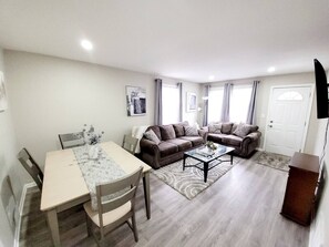Un salon comprenant une table à manger, deux canapés, une table basse et un meuble pour la télévision.