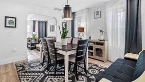 A modern dining area with a wooden table and chairs, a hanging pendant light, and a patterned rug. - Renovated 2nd-Floor Home (Boston)