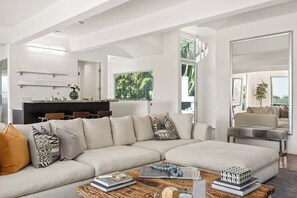 Una sala moderna con un sofá modular, una mesa de centro y una zona de comedor con sillas.
