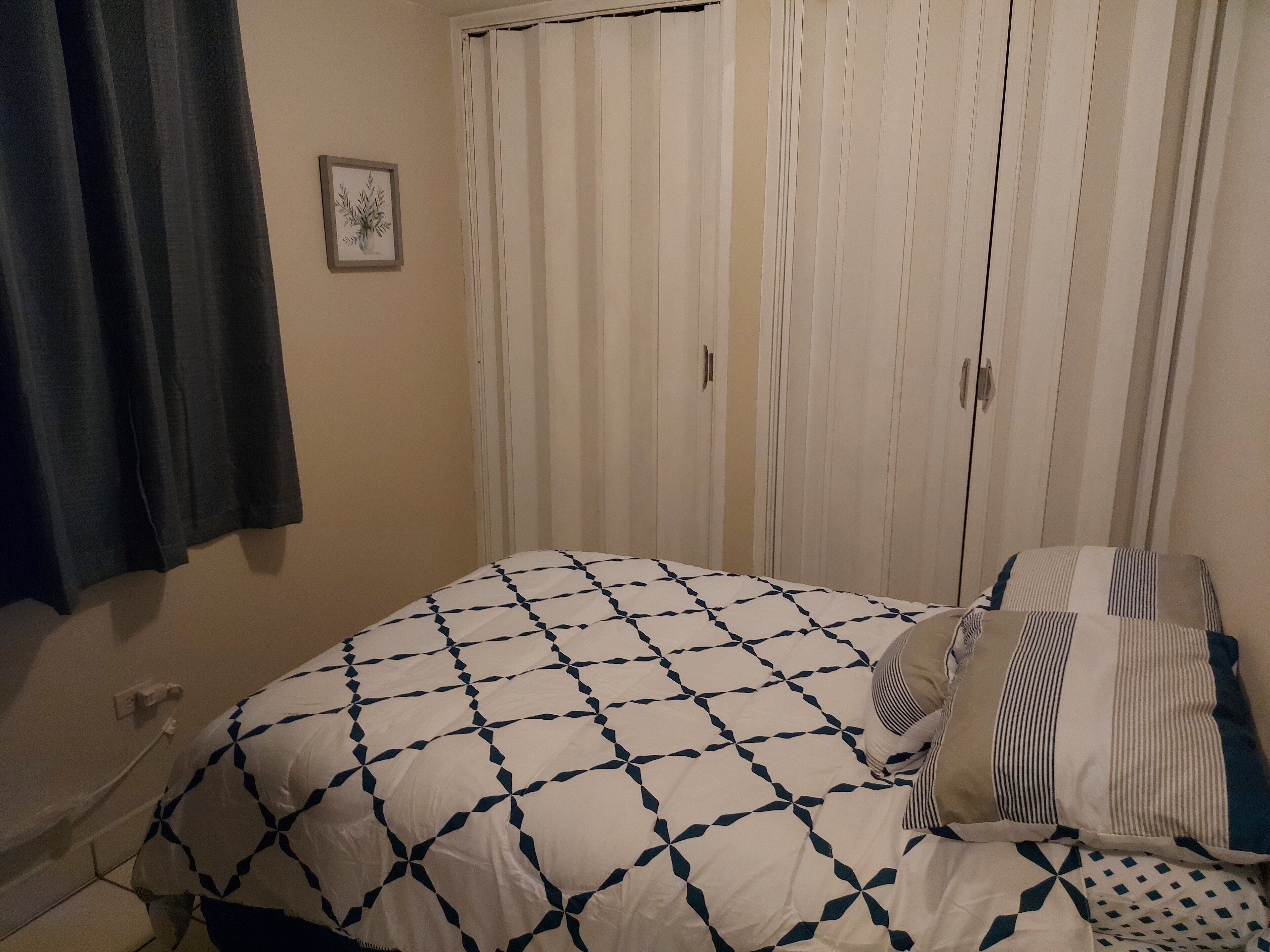 Une chambre à coucher avec un lit, une armoire et un rideau.