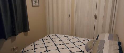 Un dormitorio con cama, armario y cortina.