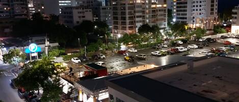 A modern building with a flat roof and large windows, surrounded by a parking area and trees.