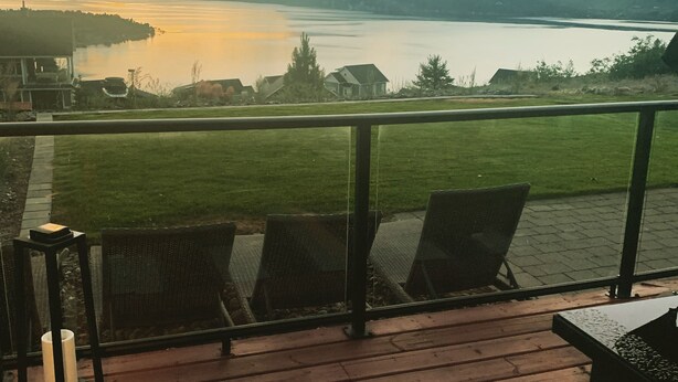 Eine Terrasse mit Sitzgelegenheit und Blick auf einen See und Berge.