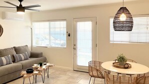 A modern living room with a sofa, coffee table, and dining area with chairs. - Air Concierge Pacific Beach Breezy Cottages #3 (San Diego)