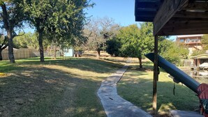 A backyard with a concrete pathway, trees, and a wooden deck. - Waterfront home with 3 bedrooms  2 baths. Boat dock. (Sunrise Beach Village)