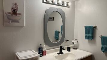 Een bad/douchecombinatie, een haardroger, handdoeken, zeep