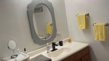 A bathroom with a vanity, a sink, a mirror, and a towel rack.