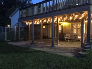 Une terrasse couverte, agrémentée de guirlandes lumineuses, avec un espace salon et une petite table.