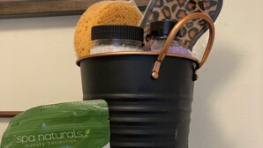 Una bañera de spa con un saquito de sales de baño y una esponja de baño con estampado de leopardo.