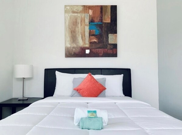 Une chambre d’hôtel avec un lit, une table de chevet, une lampe et un tableau au mur.