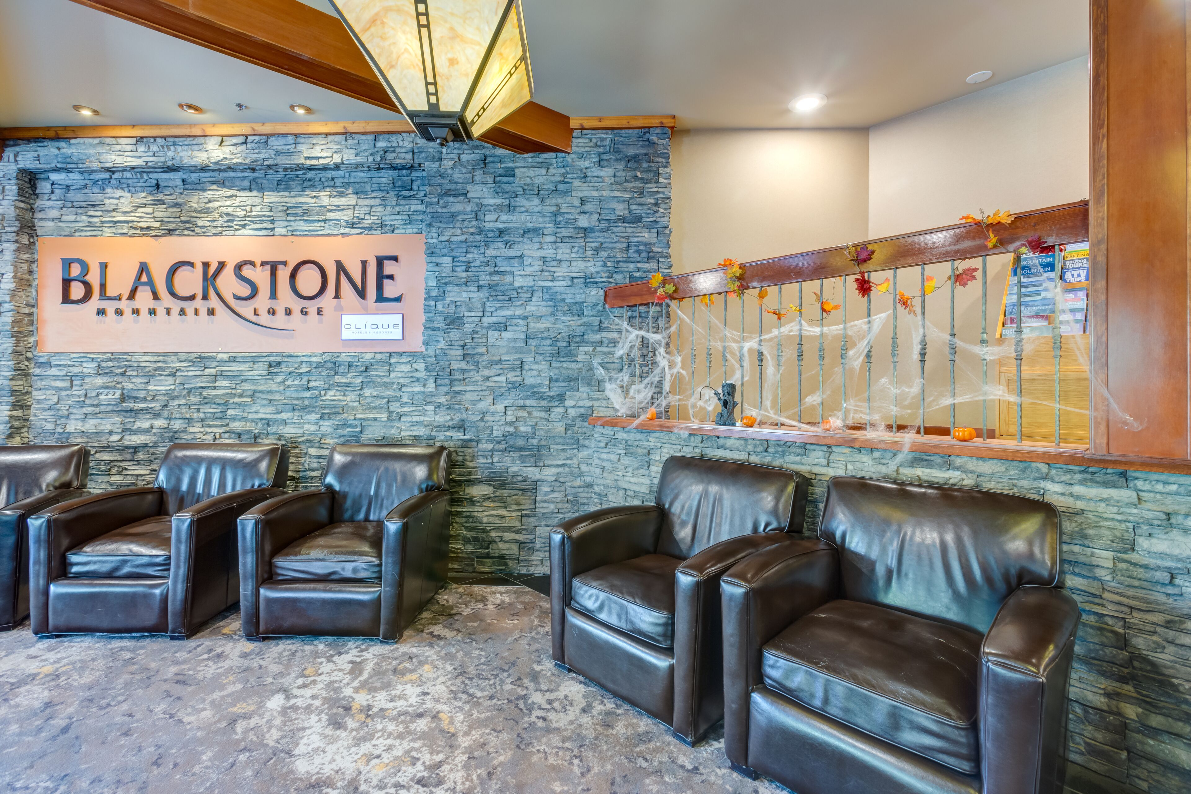 Ein Empfangsbereich mit Steinwand, einem Schild mit der Aufschrift 'BLACKSTONE MOUNTAIN LODGE' und Ledersesseln.