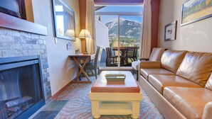 Una sala de estar acogedora con chimenea, sofá de cuero y vistas a las montañas.