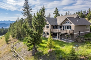 A large two-story house with a balcony, surrounded by trees and a view of mountains. - Spectacular Private Big Sky 5 Bedroom Home - BEST LOCATION ! (Big Sky)