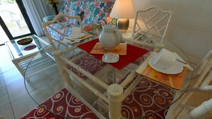 A dining area with a glass table, red patterned placemats, white chairs, and a floral sofa. - A. Parque Santiago 1-1 bed-pool-sea front location. Sunny. (Playa de la Américas)