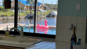 Une cuisine donnant sur une piscine, avec un flotteur en forme de flamant rose et une bouteille de champagne.
