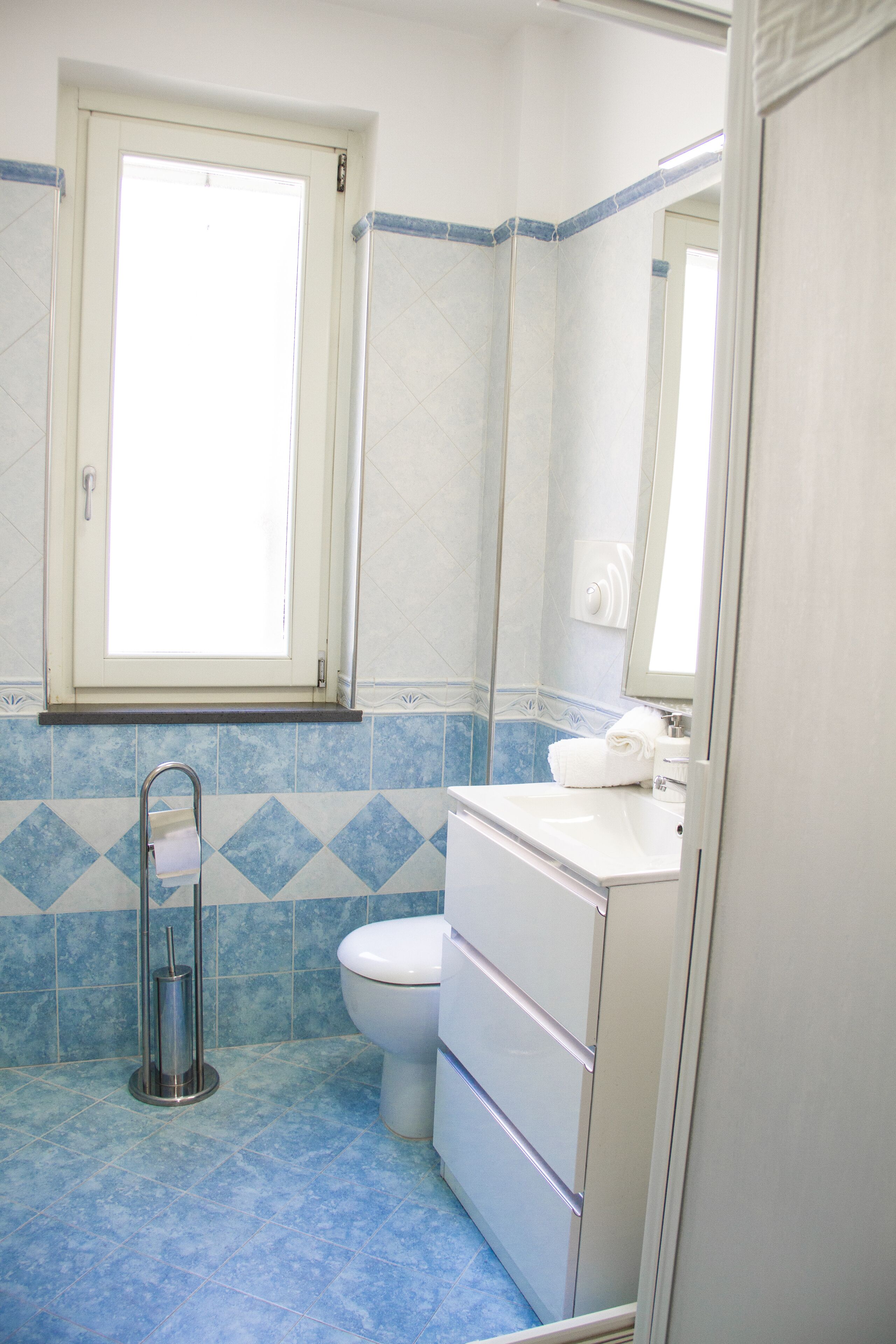 Un baño con inodoro, lavamanos y ventana.