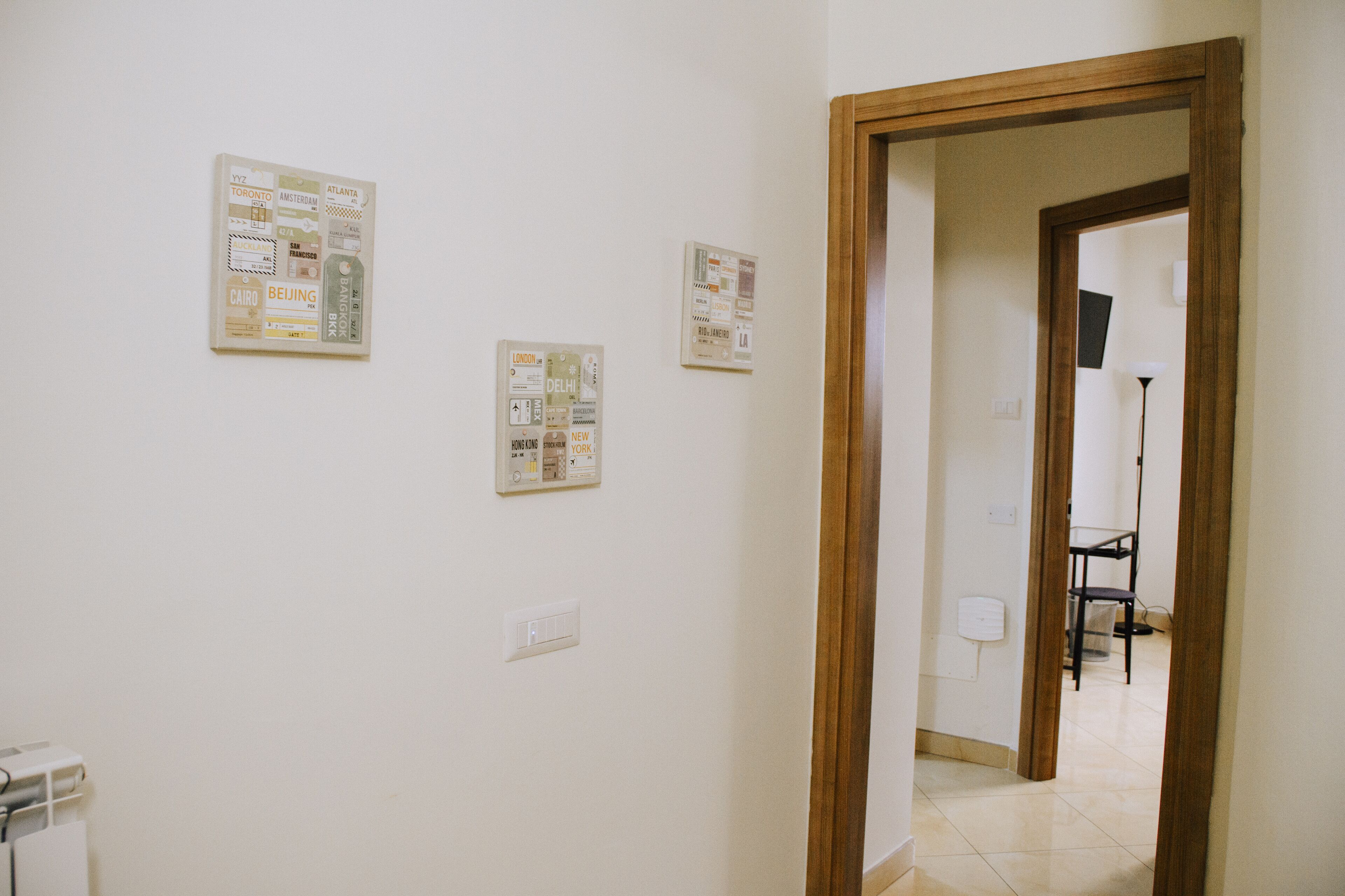 A hallway with a wooden door frame, a light switch, and three bulletin boards on the wall.