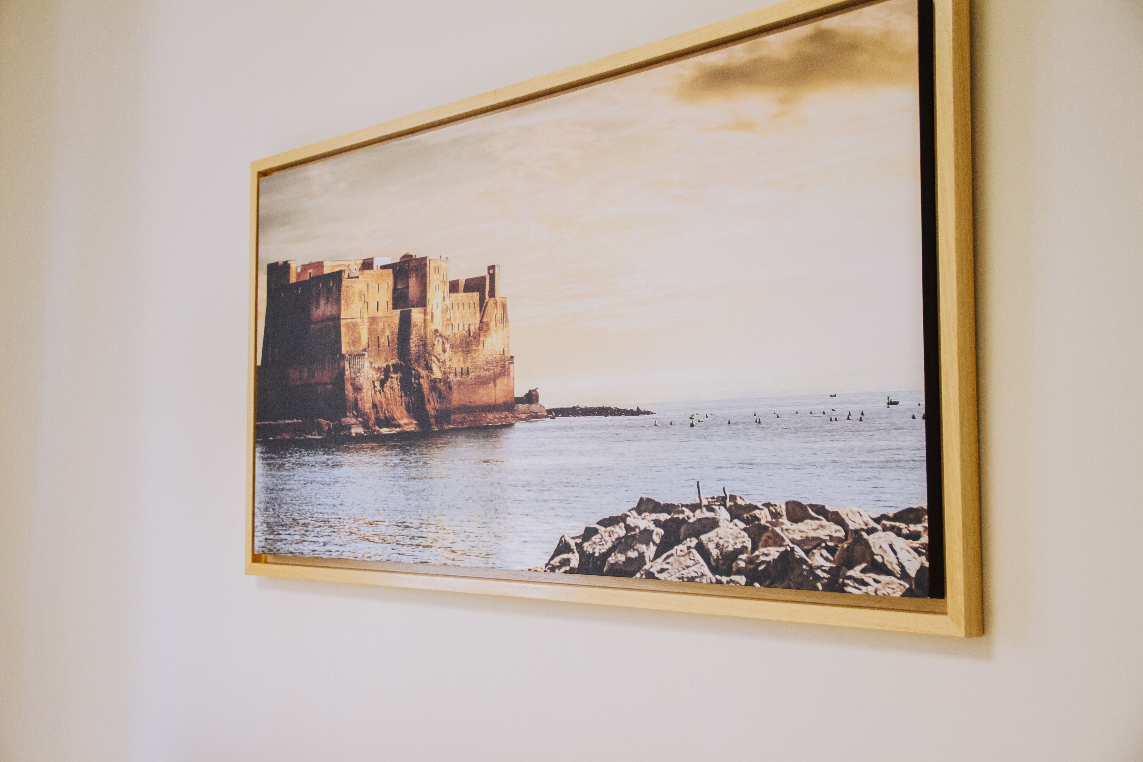 A framed photograph of a coastal scene with a large cliff and rocky shore.