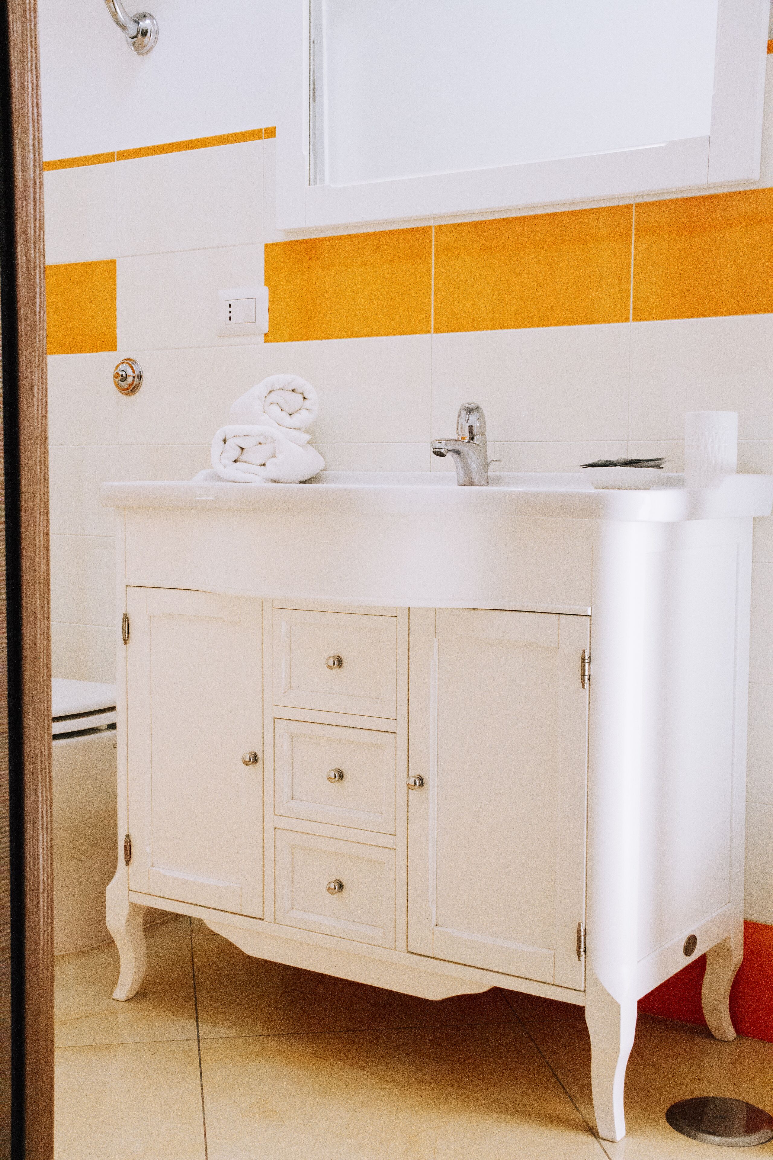 Um banheiro com toucador branco, pia e vaso sanitário.