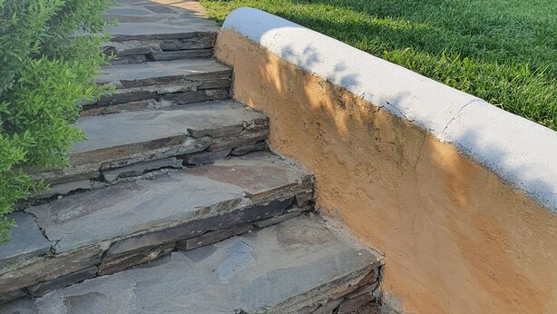 Uma escadaria de pedra que leva a um edifício com um alpendre coberto.