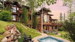 A large wooden house with a hot tub, outdoor seating, and a stone pathway. - 5 Bed/ 5.5 Bath Ski-In, Ski-Out  Home in Exclusive Two Creeks Neighborhood (Snowmass Village)