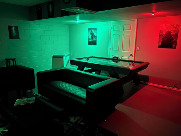 A room with a pool table, a sofa, and a small table.