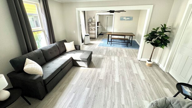 Een moderne woonkamer met een hoekbank, een eettafel en een potplant.