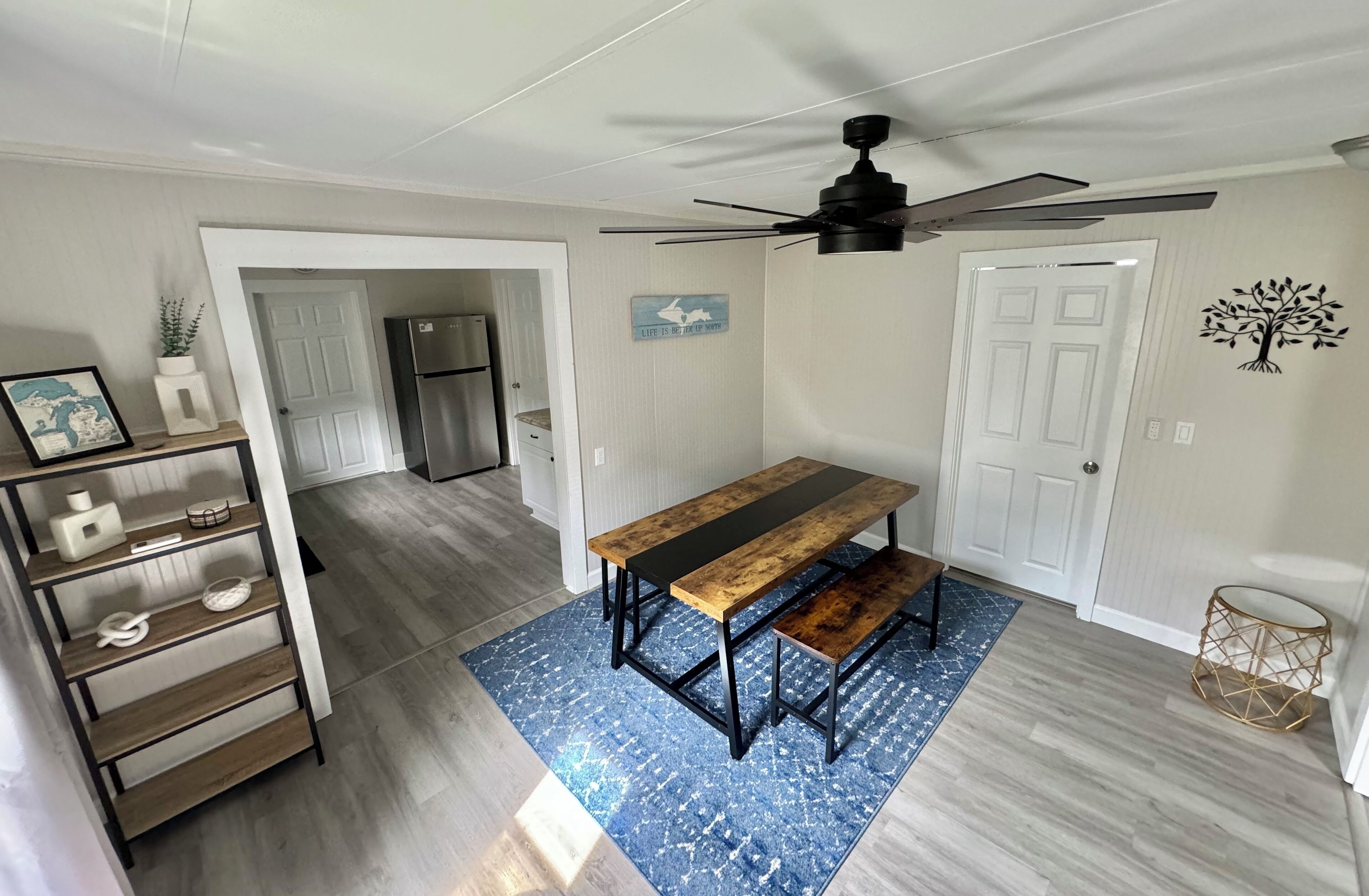 Une cuisine avec un banc en bois, un ventilateur de plafond et un tapis bleu à motifs.