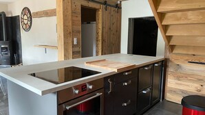 Eine moderne Küche mit Einbauherd, Backofen und einer Holztischinsel mit Schneidebrett.