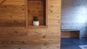 Eine Holzwand mit einer geframten Nische, in der ein kleiner Topfpflanze steht.