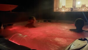 Ein Whirlpool mit roter Beleuchtung, ein Fenster mit Blick und eine Pendelleuchte.