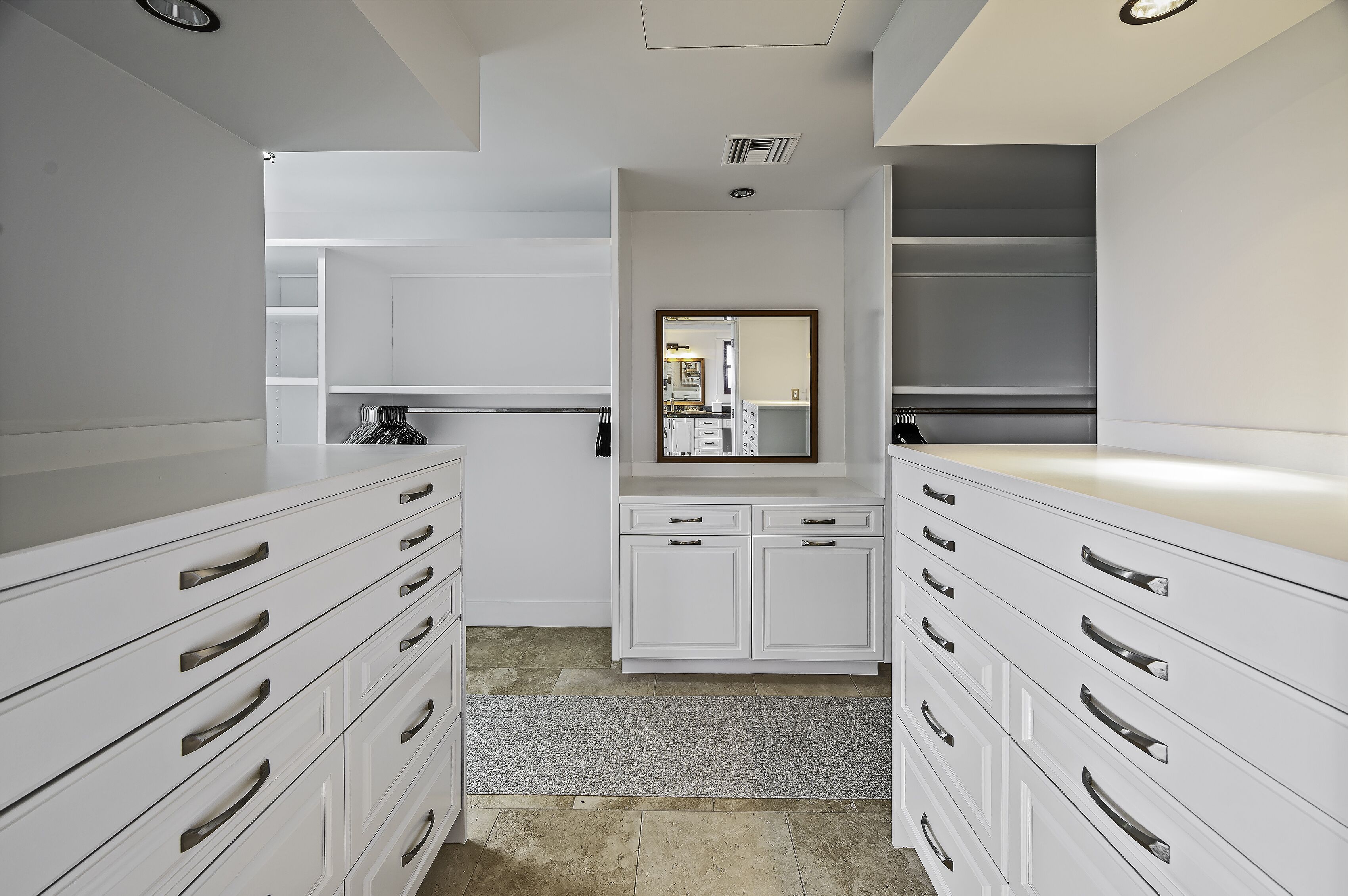 A modern bathroom with white cabinetry, a mirror, and a shower area.