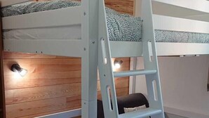 A bunk bed with a ladder, wooden wall paneling, and a small window.