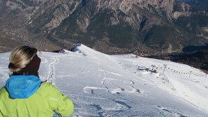A snowy mountain landscape with a ski lift and a person in a green jacket.