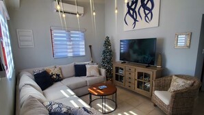 Un saló modern amb un sofà seccional, una taula de centre, una televisió i un arbre de Nadal.