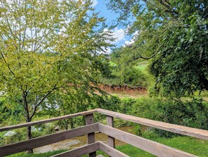 A wooden deck overlooking a natural landscape with a river and dense greenery. - Pet Friendly 4 Bedroom River Overlook on 7 Acres (Newland)