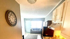 A narrow kitchen with a clock, a stove, and a sink. - Love Shak romantic beach condo , pets ok (North Myrtle Beach)