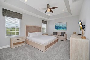 Camera da letto con un letto grande, un comodino, una scrivania, una ventola a soffitto e opere d'arte alle pareti.