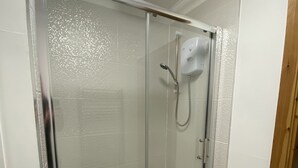 Eine begehbare Dusche mit Glaswänden, einer Handbrause und einer fest montierten Bedienkonsole.